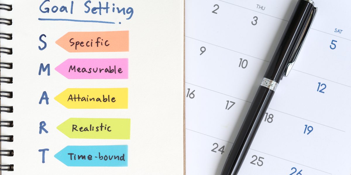 Goals written on notebook with pen and calendar
