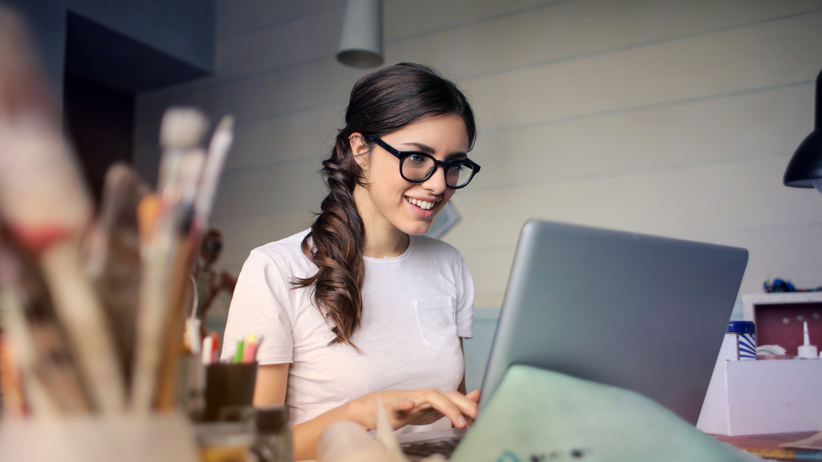 Lady in glasses looking at laptop working and smiling